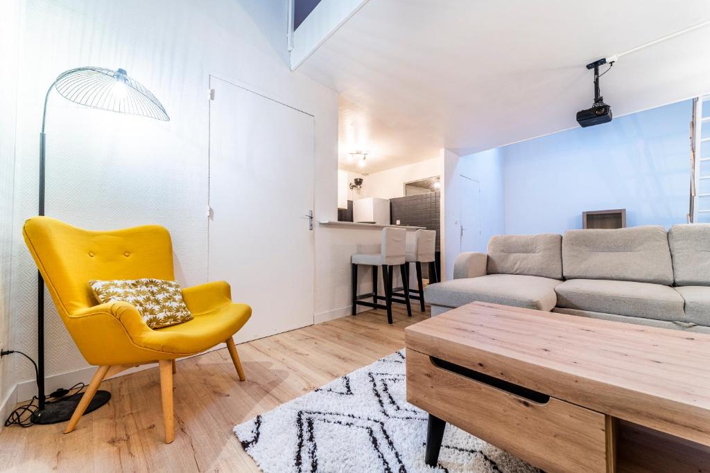 un salon avec une chaise jaune et un canapé dans l'établissement Ravissante Maison Coeur de Lille, à Lille