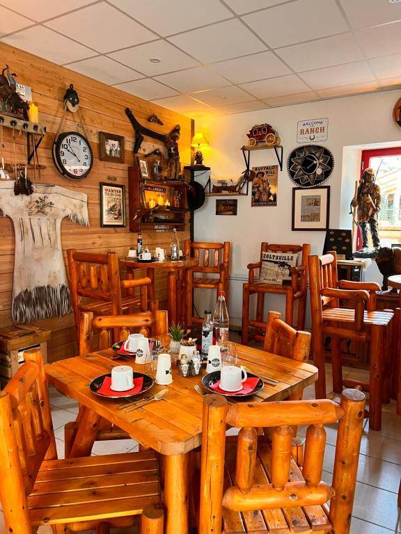een eetkamer met houten tafels en stoelen bij Hotel Le Ranch in Brûlon