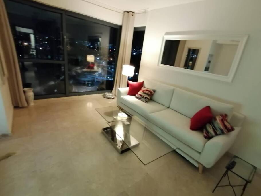 a living room with a couch and a large window at Marina towers in Herzelia 