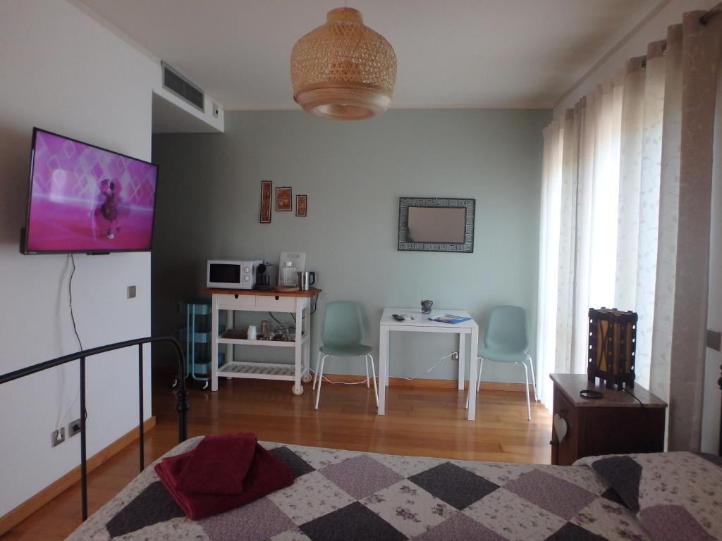 1 dormitorio con TV, mesa y sillas en Suite na Casa da Andreia, en São Martinho do Porto