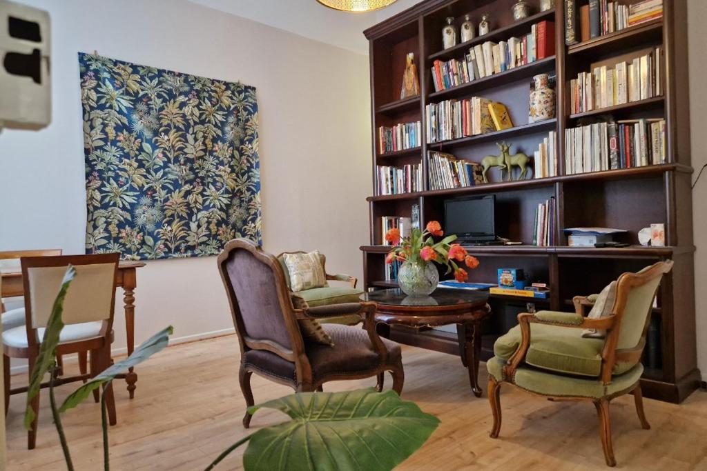a living room with a table and chairs and a book shelf at Le Pavillon Lorrain in Vittel
