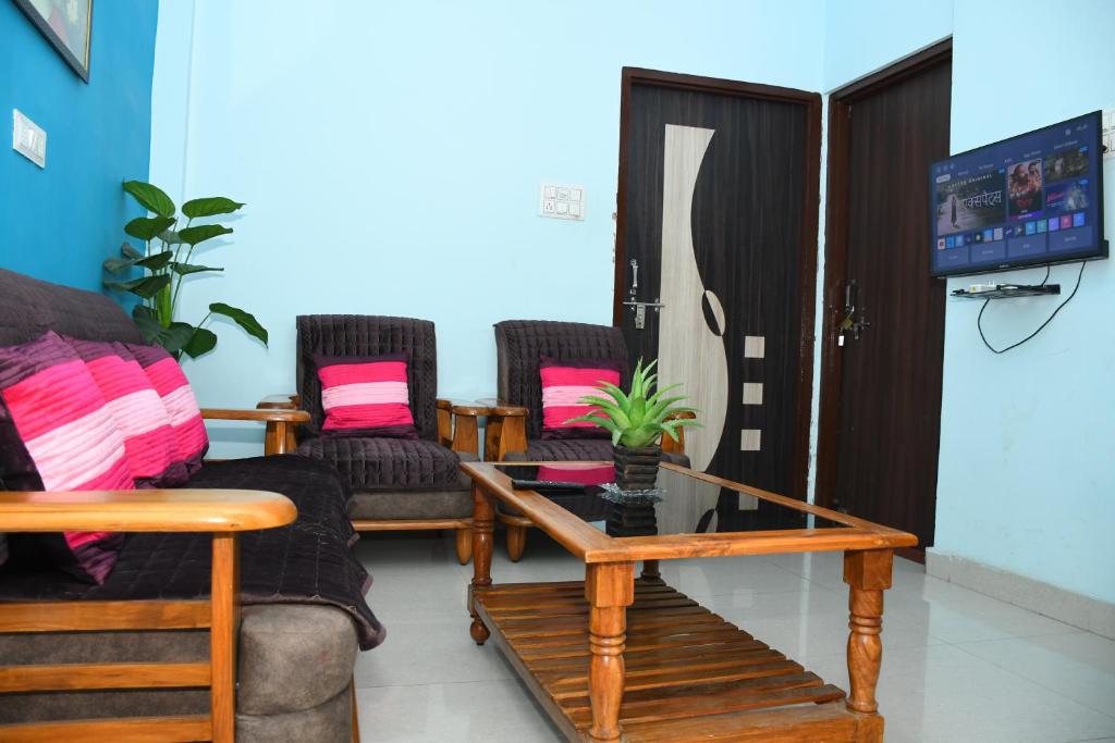 uma sala de estar com cadeiras, uma mesa e uma televisão em Indra Apartment em Varanasi