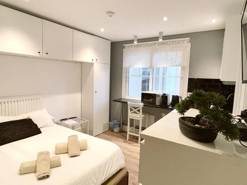 a bedroom with a white bed and a kitchen with a sink at Stylish City Centre Studio - Grand Central House in Gibraltar