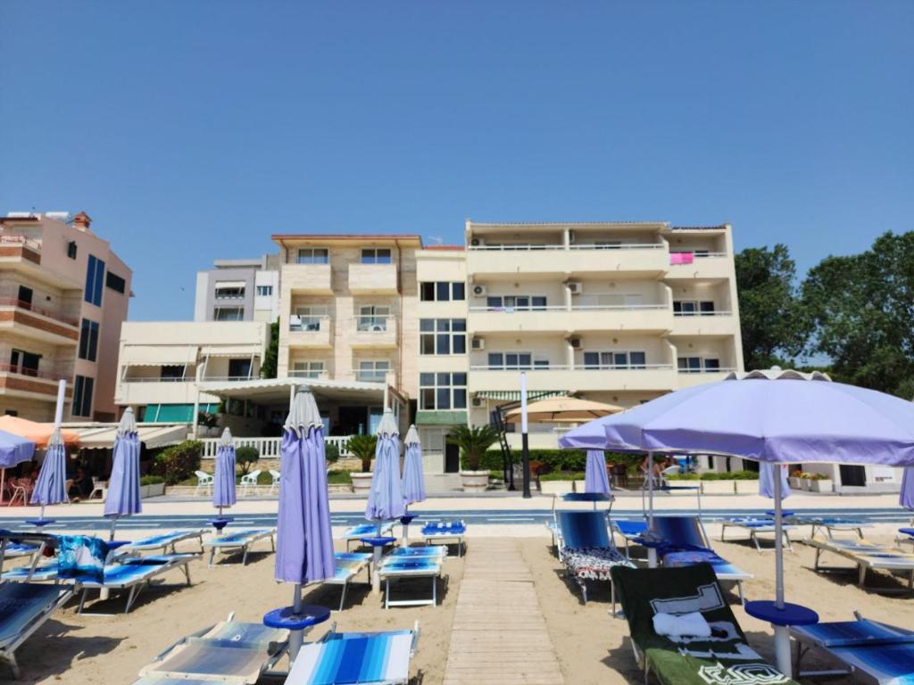 uma piscina com espreguiçadeiras azuis e guarda-sóis em Hotel Maren Durres em Durrës