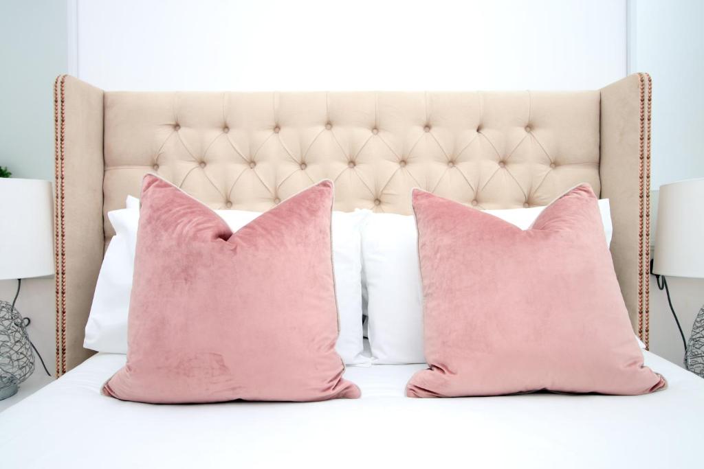 sypialnia z różowymi poduszkami na łóżku w obiekcie Charming 2BR Cardiff Oasis with Private Courtyard w Cardiff