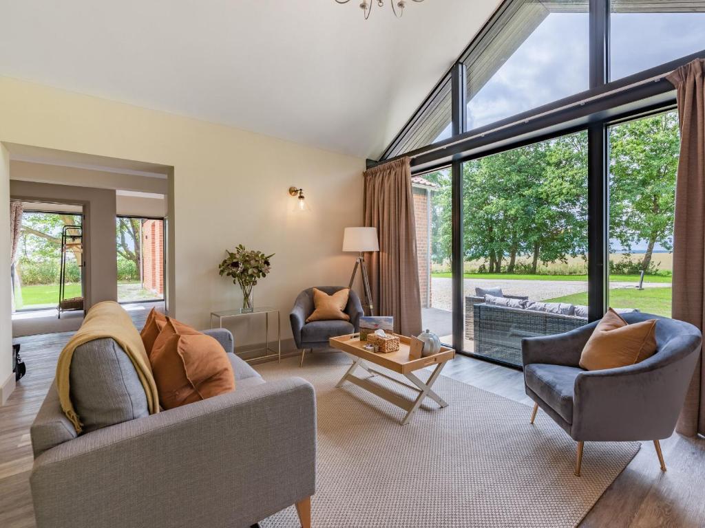 uma sala de estar com um sofá, cadeiras e janelas em Partridge em East Ilsley