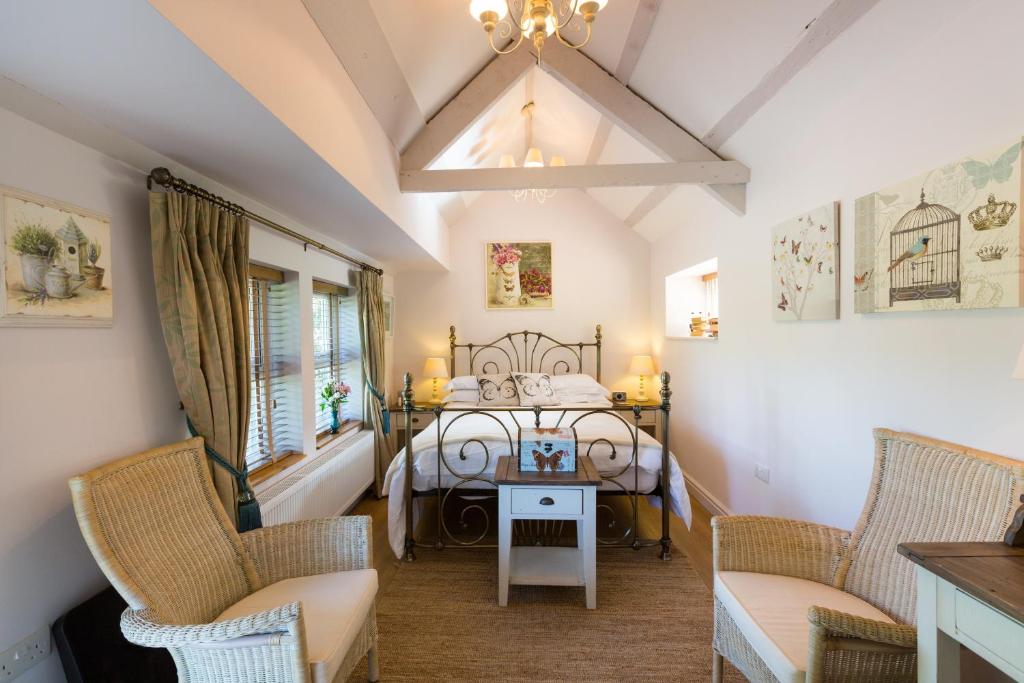 a bedroom with a bed and two chairs and a table at Penbontbren Luxury Bed and Breakfast in Aberporth