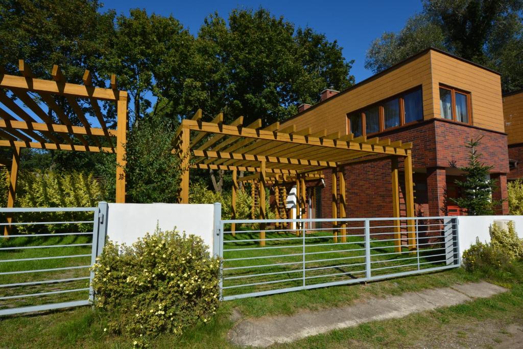 a house with a white fence in front of it at Domyletnie Sarbinowo 8e dom 86m2 z ogrodzoną działką in Sarbinowo
