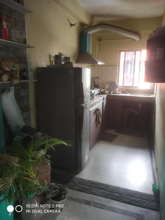 a kitchen with a refrigerator and a stove top oven at Gouri Bhawan in Kolkata
