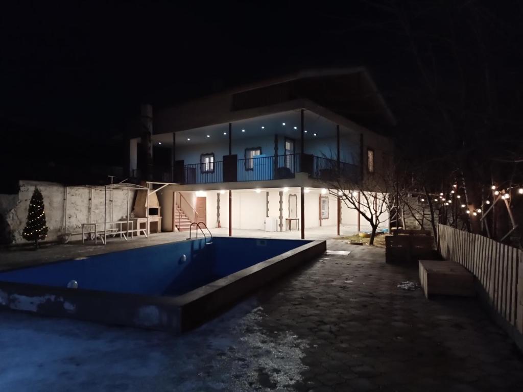 una casa con piscina por la noche en LANJ IN Eco Garden/ Guest House, en Nurrnus