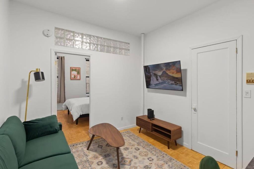 - un salon avec un canapé vert et un lit dans l'établissement Cozy 1BR in the Upper East Side, à New York