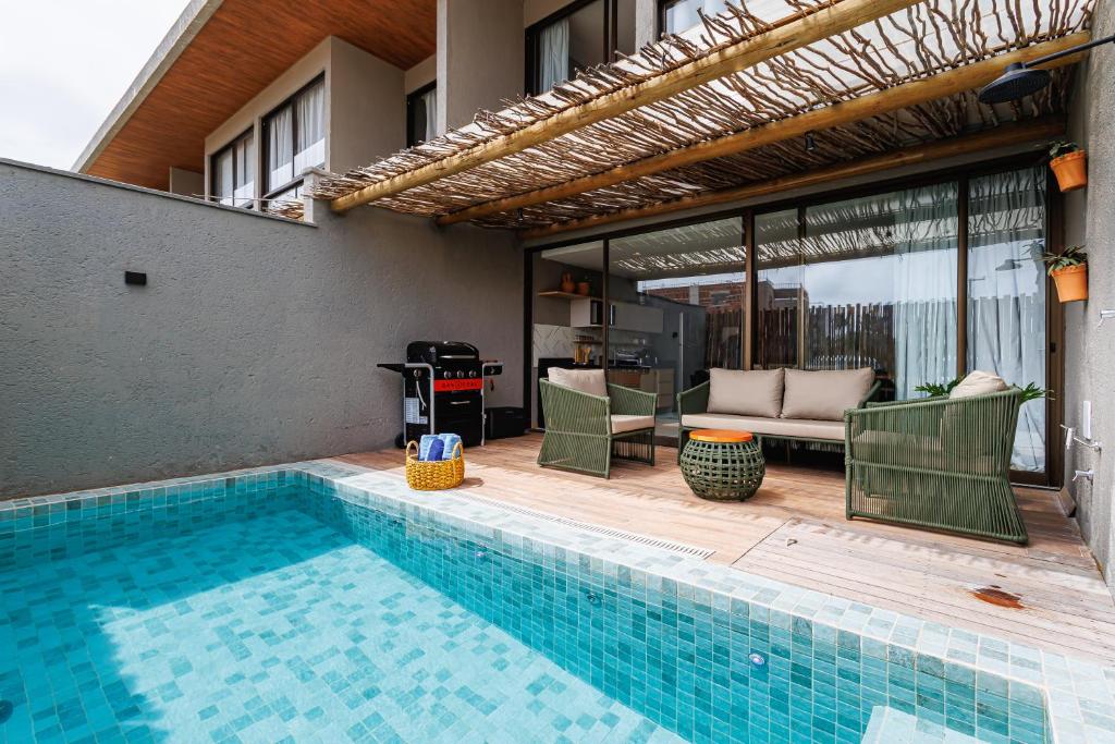 a swimming pool with chairs and a couch next to a house at Pysá Zero Um in São Miguel dos Milagres