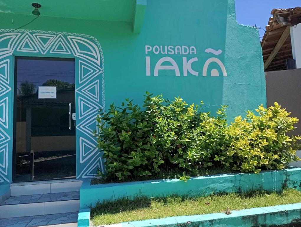 a blue building with a door and some bushes at Pousada Iakã Boipeba in Cayru