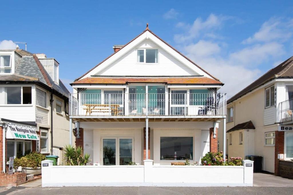 a house with a balcony on top of it at Absolute Beachfront with Decked Garden Oasis and Views in Bognor Regis