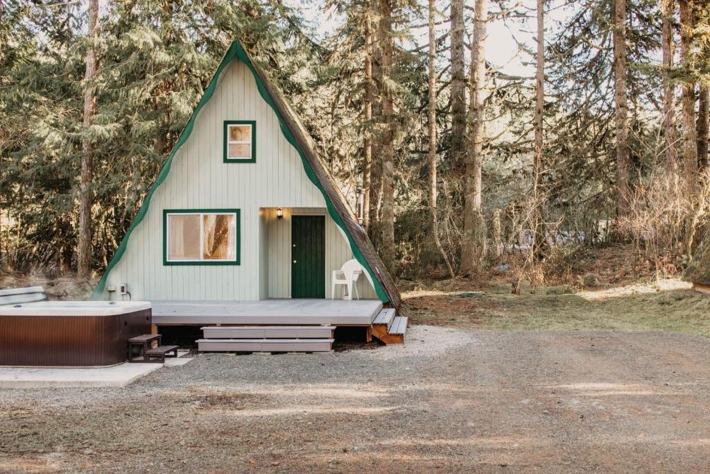 uma pequena casa verde com uma banheira em frente em 54SL - Hot Tub - Pets OK - Sleeps 4 cabin em Glacier