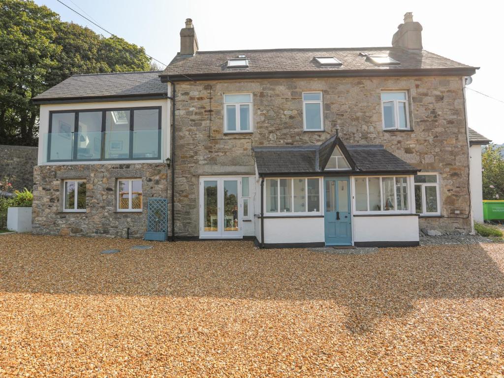 a brick house with a blue door on a gravel driveway at Gorphwysfa in Beaumaris