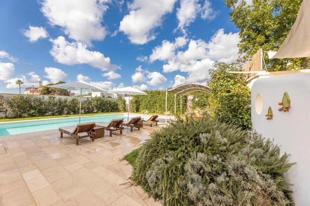 une terrasse avec une piscine, des chaises et une maison dans l'établissement Villa Estro del Sud, à Gagliano del Capo