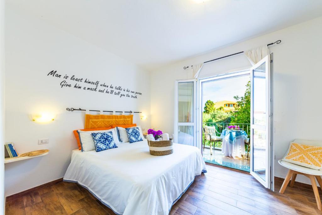 een witte slaapkamer met een bed en een balkon bij Le Maschere B&B in Santa Teresa Gallura