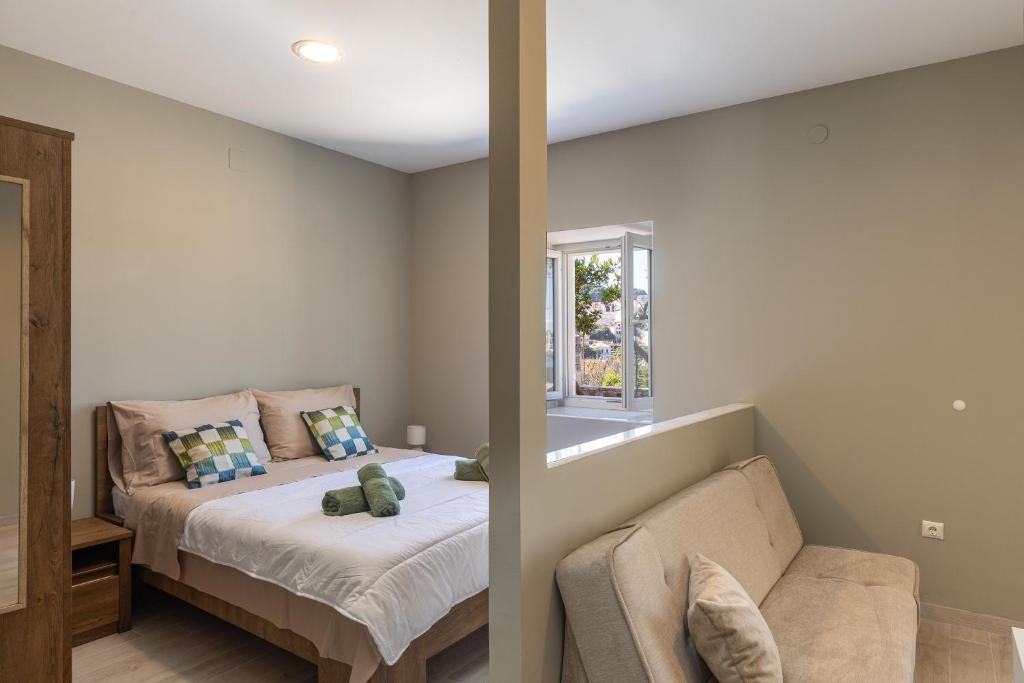 ein Schlafzimmer mit einem Bett, einem Sofa und einem Fenster in der Unterkunft Apartments Harriet in Dubrovnik
