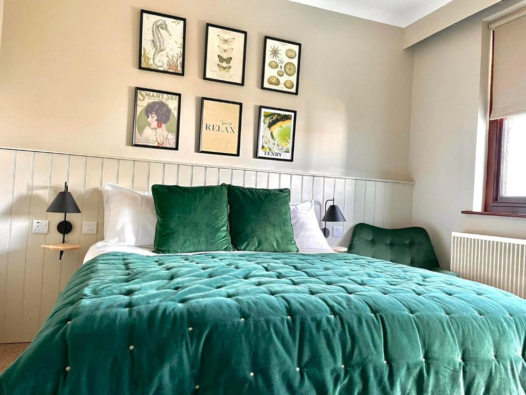 a bedroom with a bed with a green comforter at No: 1 The Esplanade Guest Accommodation. in Tenby