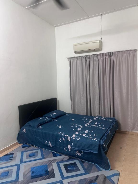 Homestay meranti في كلانغ: سرير في غرفة ذات أغطية زرقاء ونافذة
