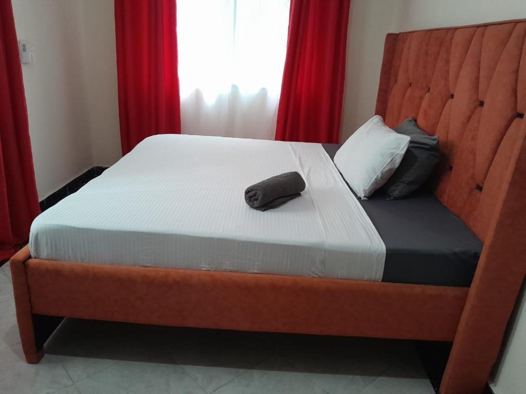 - un lit avec une tête de lit en bois et une serviette dans l'établissement Lizzy B Classic Apartments, à Mombasa