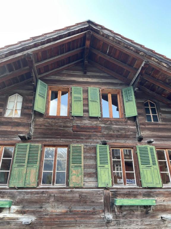 un edificio con persianas verdes y ventanas. en Charming, well-equipped Alpine apartment en Kandersteg