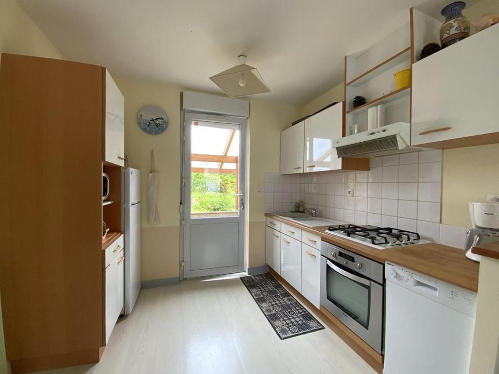 une cuisine avec des armoires blanches et un four à plaques de cuisson dans l'établissement 659 - Charmante maison en pierres, dans le centre d'Erquy,, à Erquy