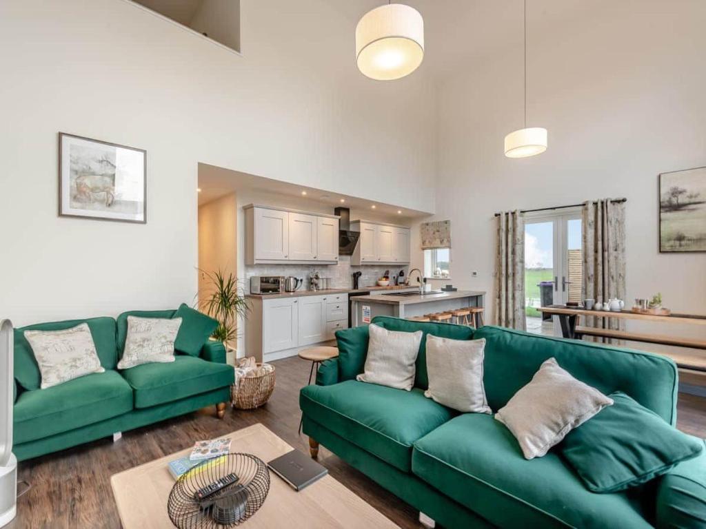 uma sala de estar com um sofá verde e uma cozinha em Pippin em Spilsby