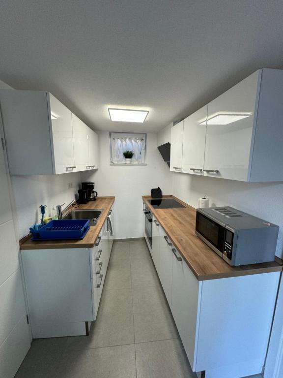 a small kitchen with white cabinets and a microwave at Ferienstüble im Zabergäu- Ferienwohnung in Brackenheim