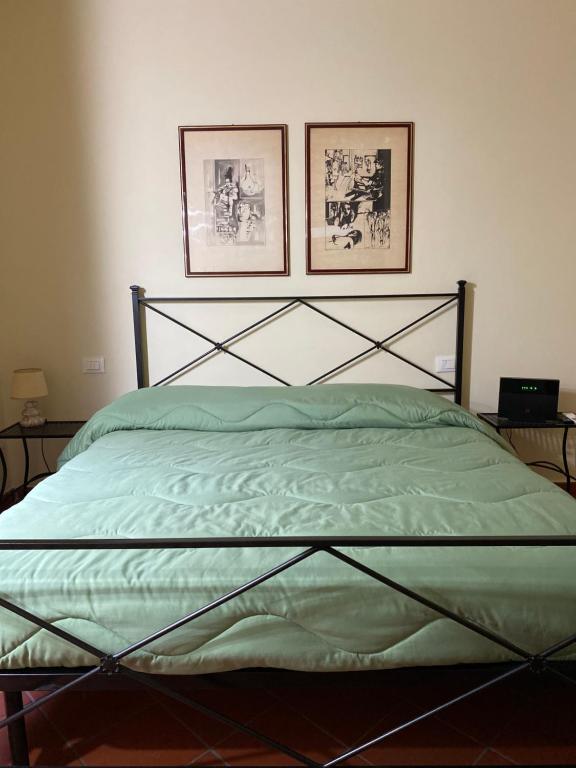 a bedroom with a green bed with two pictures on the wall at L'orologio matto in Marina di Carrara