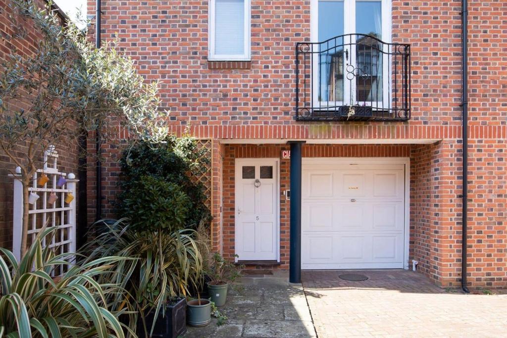 a brick house with two garage doors and a balcony at Central Chichester 3bd Mews House For Up To 6 in Chichester