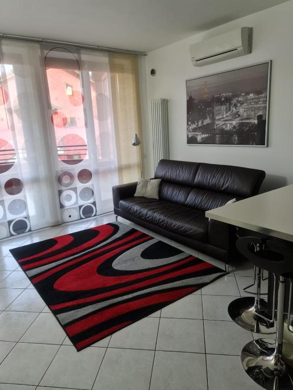 a living room with a black leather couch and a rug at Casa Camilla in Certosa di Pavia
