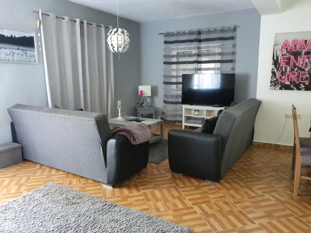 uma sala de estar com 2 cadeiras e uma televisão de ecrã plano em Bei Kostas em Mesopótamon