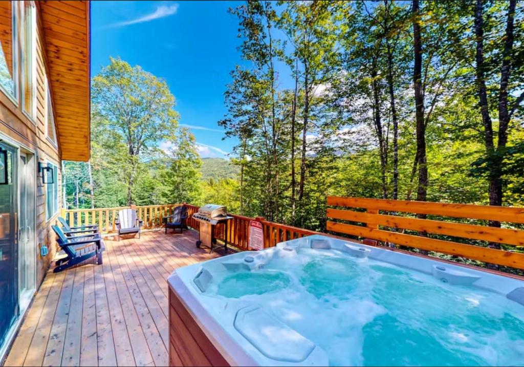 a hot tub on the deck of a house at Scoot Cabin - Dogs Welcome! in Carrabassett
