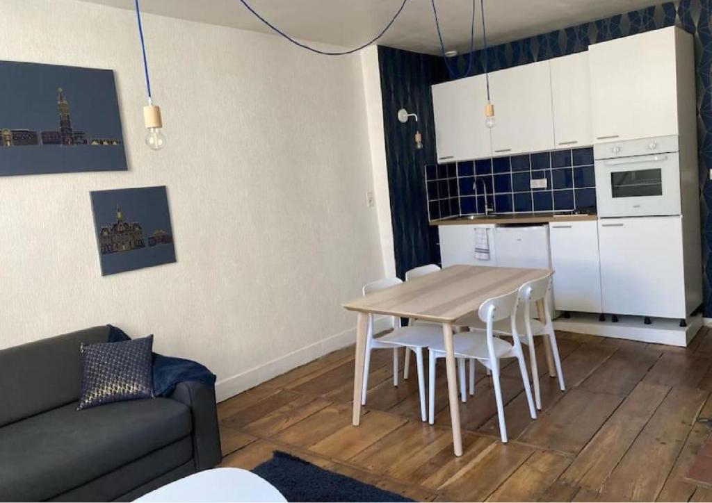 a living room with a table and a kitchen at Logement cosy en hyper-centre in Limoges