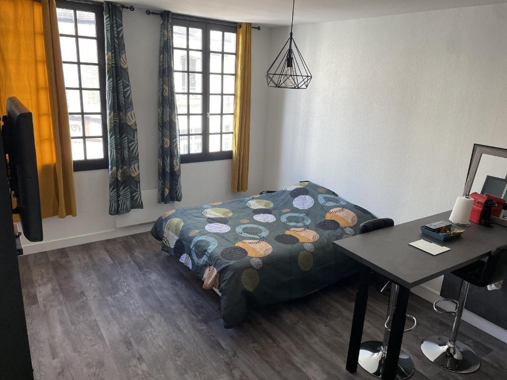 een kamer met een bed, een tafel en ramen bij Joli studio en cœur de ville in Limoges