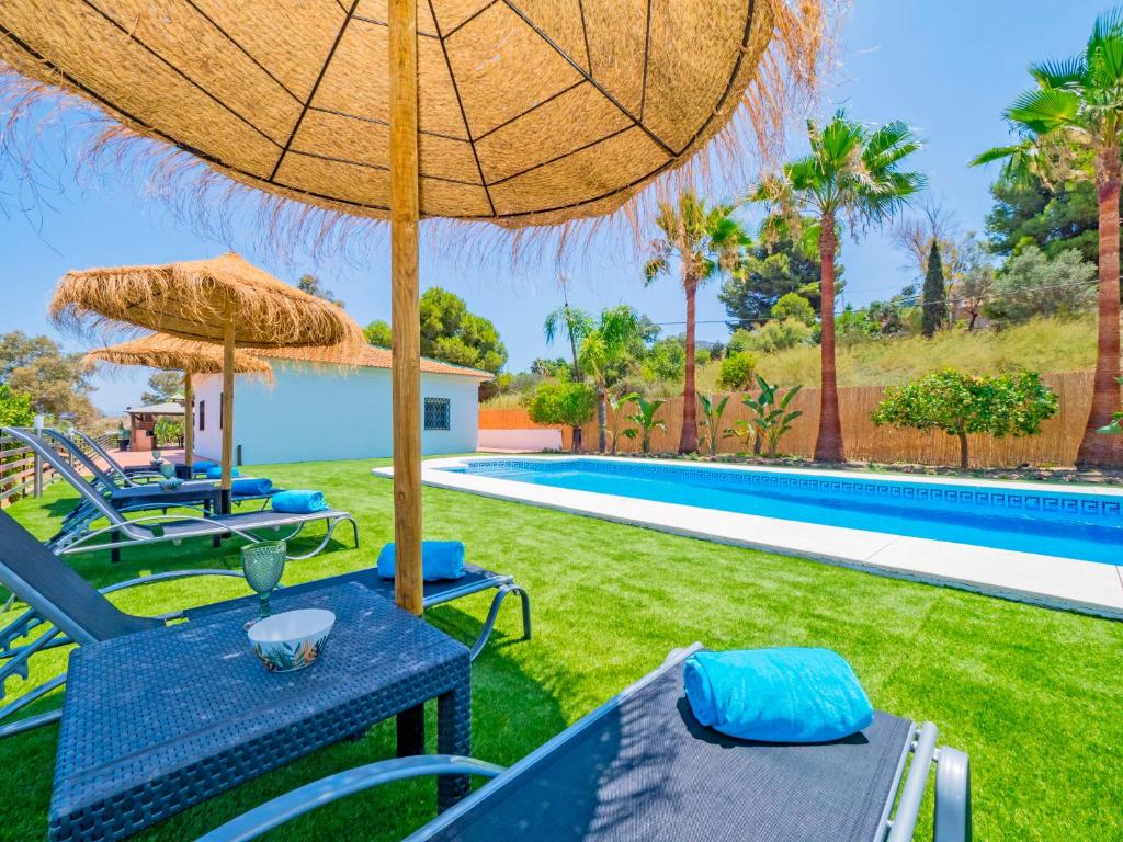 a patio with chairs and umbrellas next to a swimming pool at Cubo's Lemon House in Cártama
