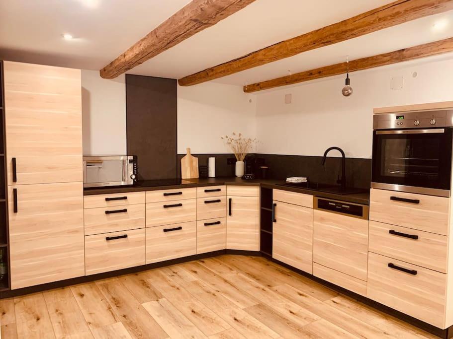 a large kitchen with wooden cabinets and appliances at Ferienhaus Allgäu Flughafen Memmingen in Benningen