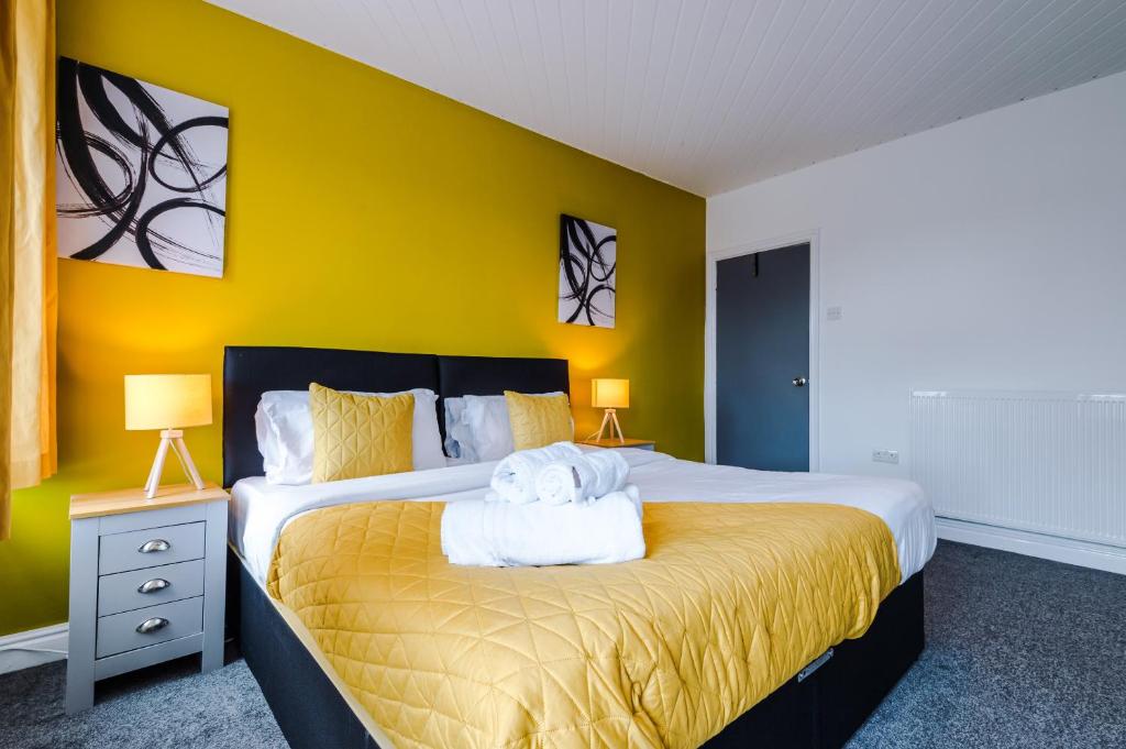 a bedroom with a large bed with a yellow wall at Barnes House - Sleeping 8 in Clayton le Moors