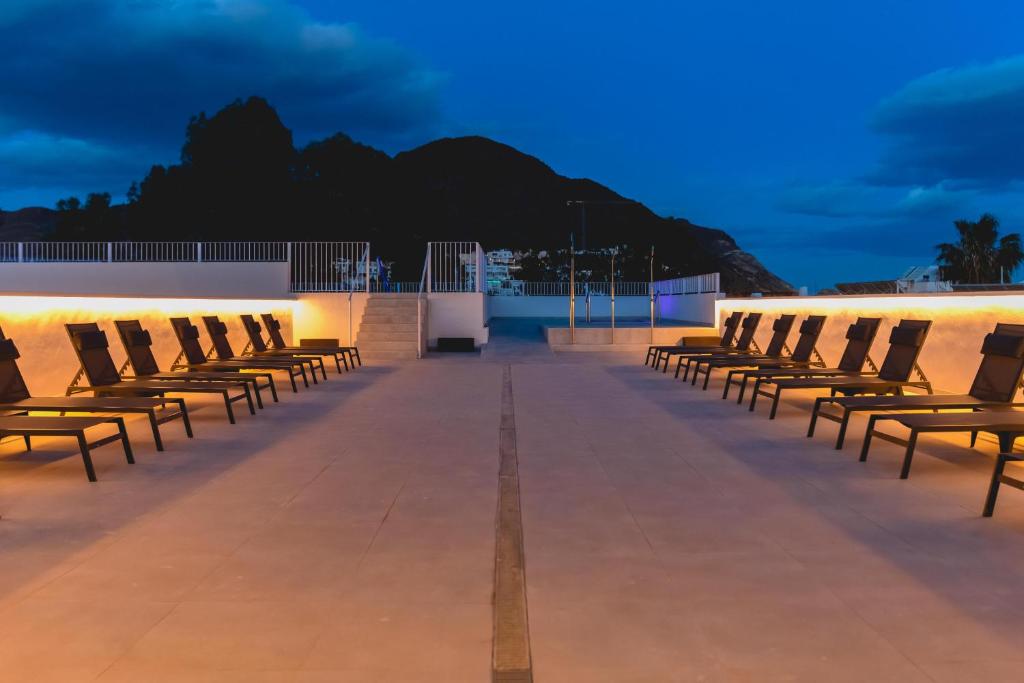 a row of chairs sitting on a roof at night at HOTEL ALOVE in San José