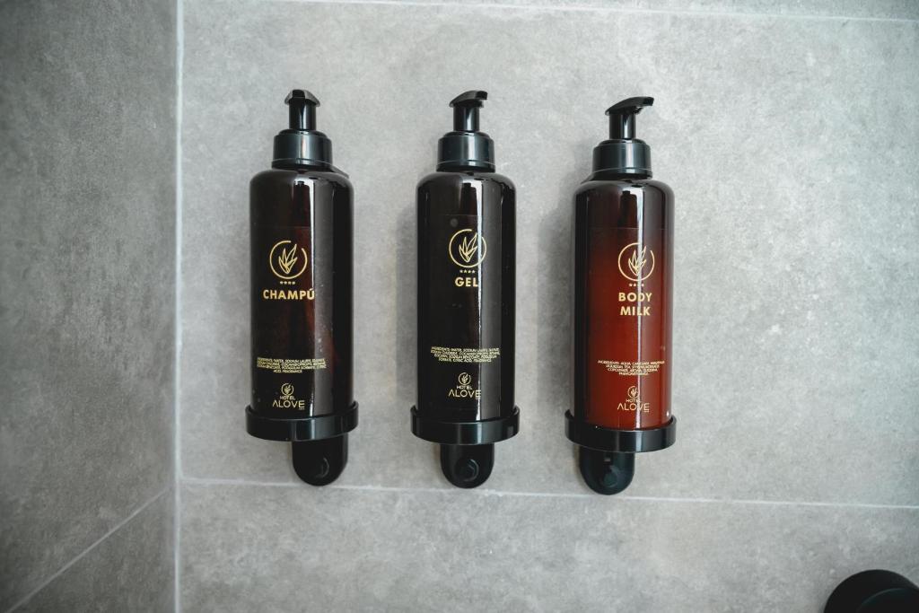 three black and brown bottles sitting on a tile floor at HOTEL ALOVE in San José