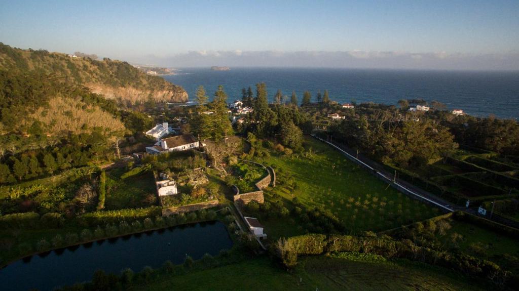 una vista aérea de una casa en una colina junto al agua en WelcomeBuddy - Casa do Monte - Garden & Sea sight, en Caloura
