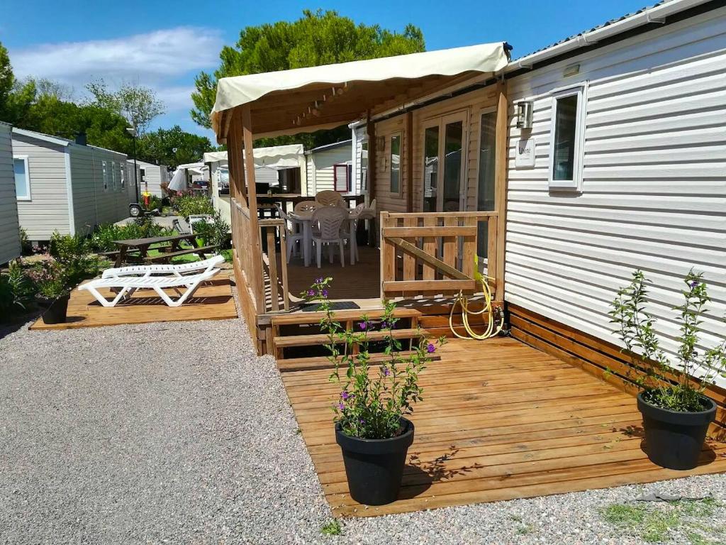 a deck on the side of a tiny house at Bungalow ensoleillé à Canet-en-Roussillon avec piscine partagéeA in Canet-en-Roussillon