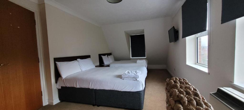 1 dormitorio con 1 cama con sábanas y almohadas blancas en Reading Budget Apartments en Reading