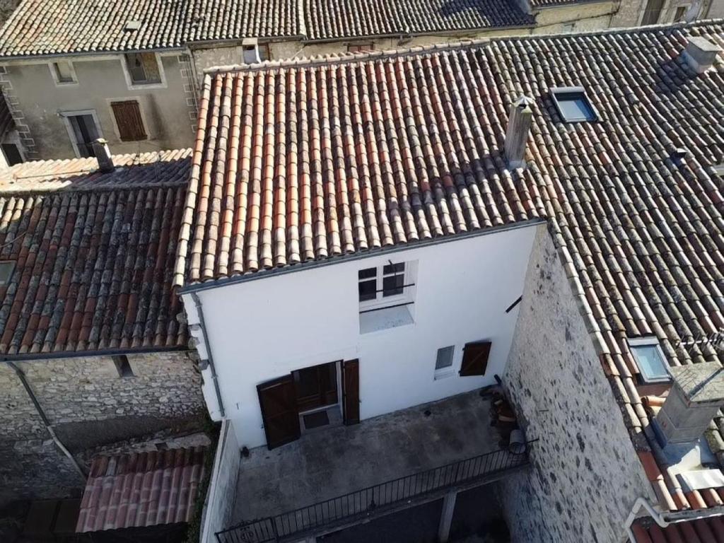 une vue sur un bâtiment blanc avec des toits bruns dans l'établissement Maison rénovée entre coeur de village et garrigue, à Saint-Martin-de-Londres
