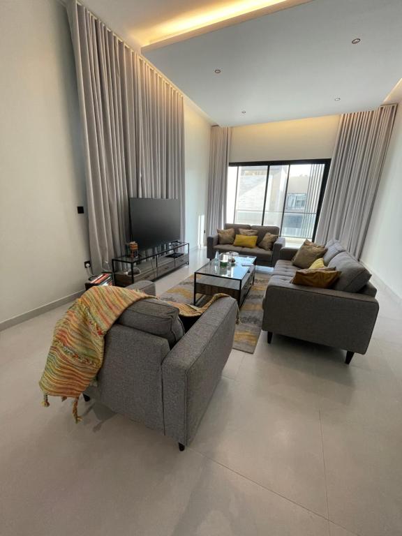sala de estar con 2 sofás y TV en شقه ذات سقف مرتفع لغير المدخنين في النرجس en Riad