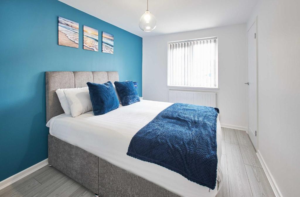 a bedroom with a large bed with blue walls at Host & Stay - Marsden Beach House in South Shields