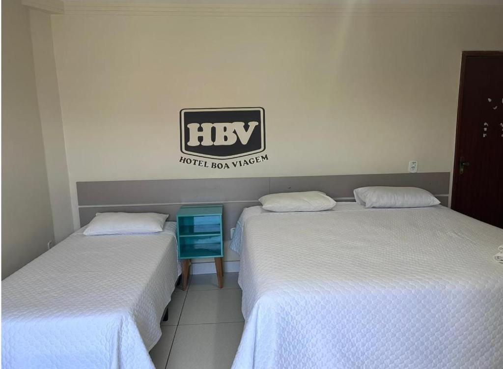two beds in a room with a sign on the wall at Hotel Boa Viagem in Barra do Garças