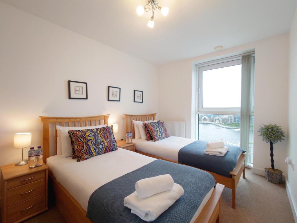 two beds in a hotel room with a window at London ExCeL Stays - Three Bed Serviced Apartment in London